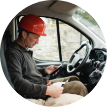 ლიოტონი®  1000 გელი  სამსახურში მამაკაცი, რომელსაც წითელი ჩაფხუტი ახურავს, სატვირთო მანქანაში ზის და ტელეფონს ამოწმებს.